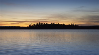 Silhouette of trees and lake at sunset