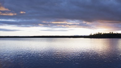 Silhouette of trees and lake at sunset