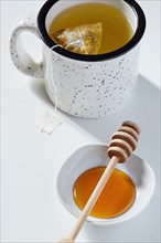 Cup of tea, honey dipper and bowl of honey