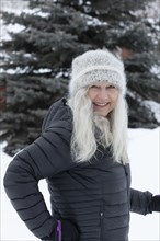 Smiling woman wearing hat and jacket in snow