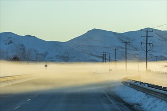 Fog on road by snowy mountains