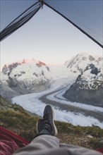 Man lying inside tent with Gorner Glacier in distance in Valais, Switzerland