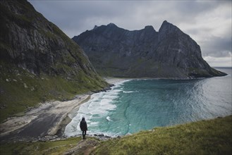 Man standing on rock by Kvalvika Beach in Lofoten Islands, Norway