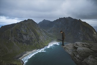 Man standing on cliff at Ryten mountain in Lofoten Islands, Norway