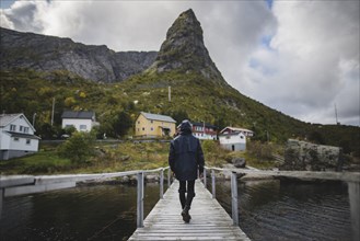 Man walking on bridge by cliff in Lofoten Islands, Norway