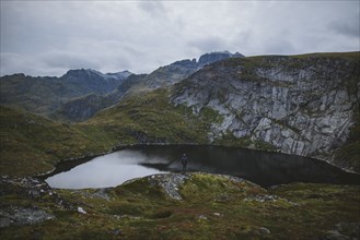 Man standing on rock by lake in Lofoten Islands, Norway