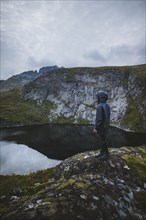 Man standing on rock by lake in Lofoten Islands, Norway