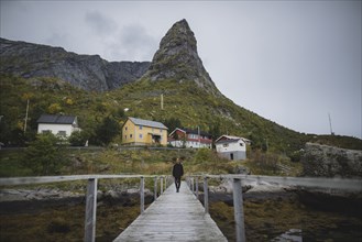 Man walking on bridge by cliff in Lofoten Islands, Norway