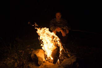 Man sitting by campfire at night