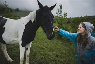 Smiling woman petting Icelandic horse