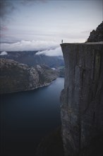 Person standing on Preikestolen cliff in Rogaland, Norway