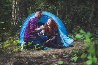 Smiling couple drinking by tent