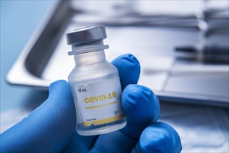 Close-up of gloved hand holding vial of Covid-19 coronavirus vaccine