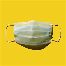 Surgical mask against yellow background