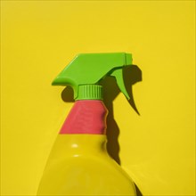 Colorful plastic spray bottle on yellow background
