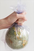 Hand holding earth globe in plastic bag