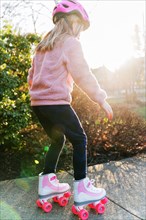 Little girl rollerskating in sunny day