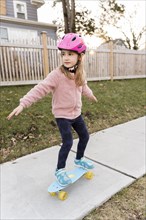 Girl skateboarding down on sidewalk