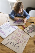 Girl coloring protest signs for women's march
