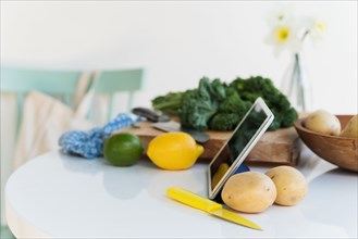 Tablet and vegetables on table