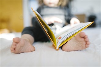 Barefoot girl (2-3) reading book