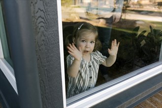Girl (2-3) looking through window