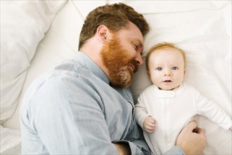Father and baby boy (2-3 months) lying on bed