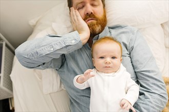 Father lying on bed with baby boy (2-3 months)