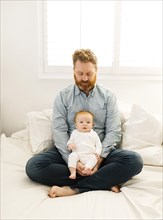 Father sitting on bed with baby boy (2-3 months)