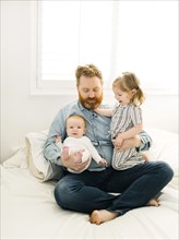 Father sitting on bed with children (2-3 months, 2-3)