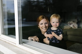 Mother and daughter (2-3) looking through window