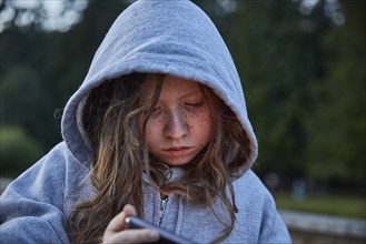 Girl in hoodie using phone