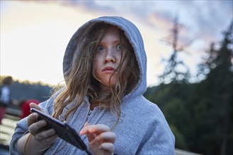 Girl in hoodie using phone