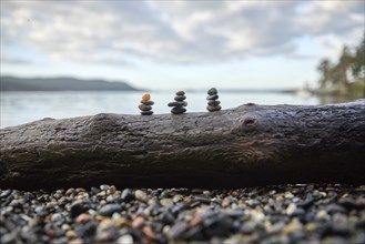 USA, Washington, San Juan County, Orcas Island, Stacks of pebbles on log