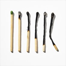 Row of burnt matchsticks on white background