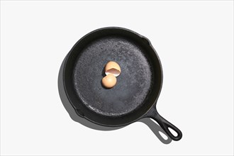 Overhead view of egg shells on frying pan on white background