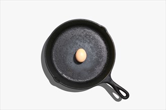 Overhead view of whole egg on frying pan on white background