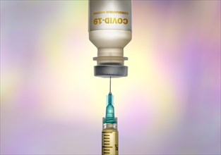 Covid-19 vaccine and syringe on colorful background