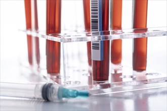 Studio shot of Covid-19 blood samples in test tube rack and syringe