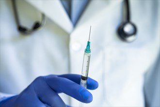 Close-up of gloved doctors hand holding syringe