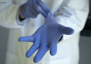 Close-up of doctor putting on blue latex gloves