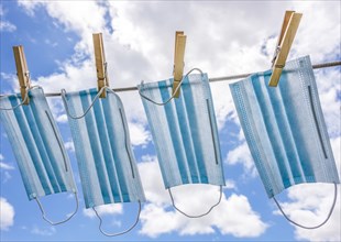 Row of surgical masks hanging on clothesline with sky in background
