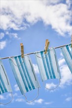 Row of surgical masks hanging on clothesline with sky in background