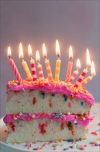 Slice of birthday cake with lit candles
