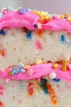 Colorful sprinkles on pink cake frosting