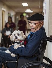 Senior man in wheelchair holding service dog
