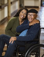 Daughter embracing senior father in wheelchair