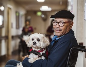 Senior man in wheelchair holding service dog