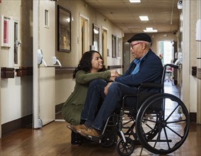 Daughter holding hands with senior father in wheelchair