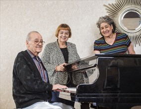 Senior women listening to man playing piano